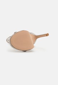 Korkokenkä, jossa on metallinen verkko-osa, jossa on monimutkaisia läpivientiyksityiskohtia, sileä beige pohja ja kapea korko.