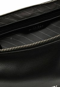 Schwarze Lederhandtasche mit strukturierter Oberfläche, ausgestattet mit einem Reißverschluss und einem gefütterten Innenraum mit horizontalen Streifen. Logo prägte innen.
