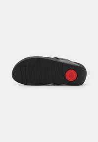 Zwart sandaal met een textured rubberen zool. Bevat een rode cirkelvormige accent en het reliëf 'fitflop' logo. Glad materiaal met gebogen vormen.