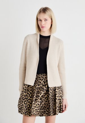 Beige ribbed knit cardigan with open front, paired with a black sheer top and a pleated leopard print skirt featuring brown and black patterns.