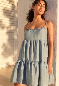 Himmelblaues, ärmelloses Kleid aus weichem Stoff, mit einem gerafften Ausschnitt und einem weit ausgestellt Rock im Stufendesign.