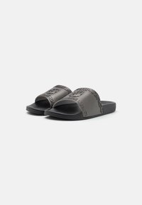 Szare klapki z teksturowanym paskiem z wytłoczonym wzorem. Miękka wkładka i płaska gumowa podeszwa dla wygody.