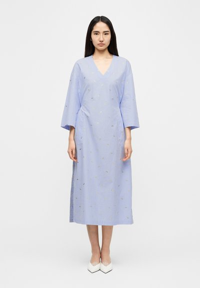 Φόρεμα σε στυλ κιμονό με γαλάζιες ρίγες, V-λαιμόκοψη, φαρδιά μανίκια και χρυσές λεπτομέρειες. Το ύφασμα φαίνεται απαλό, με άνετη εφαρμογή και πλευρικές σκισίματα.