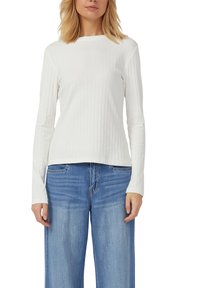 Weißes, geripptes Langarmshirt mit rundem Ausschnitt, kombiniert mit hellblauen Jeans mit weitem Bein. Der Stoff wirkt glatt und leicht schimmernd.