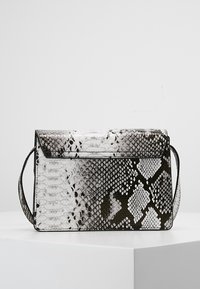 Obdélníková kabelka s černým, bílým a šedým hadím vzorem a úzkým ramenním popruhem, umístěná na bílém podstavci.