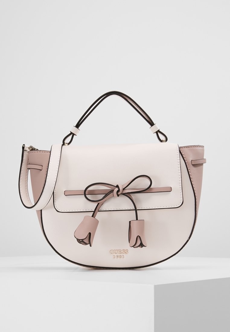 Sac à main beige clair avec une poignée supérieure, une bandoulière amovible, et un nœud décoratif avec deux extrémités en forme de tulipes sur le rabat avant.