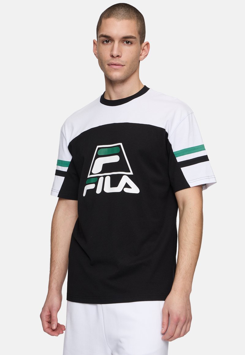 Svart och vit t-shirt med kort ärm och gröna randiga detaljer, samt en framträdande FILA-logotyp på framsidan. Tillverkad av bomullstyg.