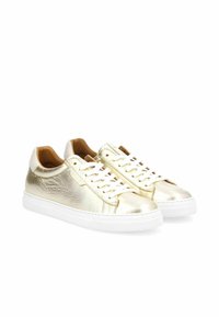 Sneaker metallici oro con texture liscia, lacci bianchi e suola in gomma bianca. Il tallone posteriore presenta un accento bianco a contrasto.