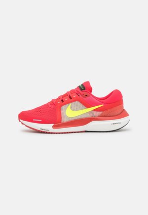 Nike running shoe in vibrant pink and yellow. Features mesh upper, padded collar, and rubber sole with textured grip. ZoomX cushioning.