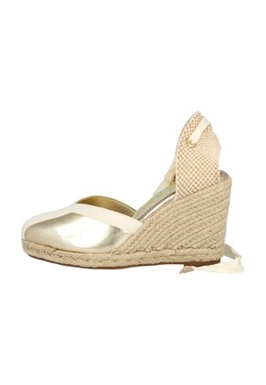 Alpargatas de cuña metálicas doradas con suela de yute trenzado. Cuentan con una correa de tela y una parte trasera texturizada con un lazo.