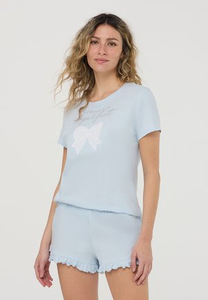 Pigiama corto azzurro chiaro con maniche corte, caratterizzato da un fiocco ricamato bianco sulla maglietta e bordi ondulati sui pantaloni. Materiale in cotone morbido.