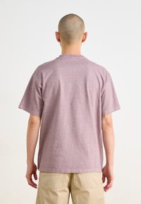 Tričko s krátkym rukávom a voľným strihom v odtieni mauve, vyrobené z jemnej zmesi bavlny. Má okrúhly výstrih a minimálne švy.