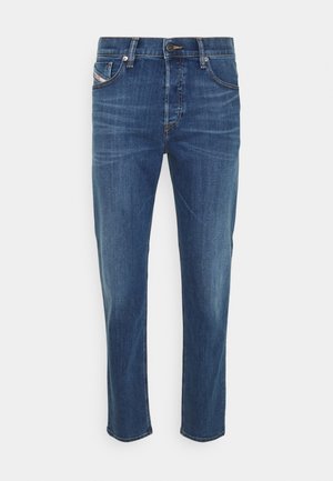 Niebieskie dżinsy denim o prostym kroju, z przednimi kieszeniami, szlufkami na pasek i zapięciem na guziki na białym tle.