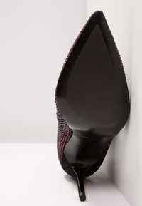 Scarpa stiletto nera con tomaia in tessuto texturizzato dai motivi rossi e grigi, punta affusolata e una suola nera lucida e raffinata.
