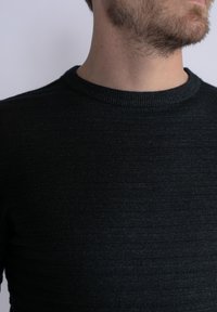 Maglione nero a maglia con una finitura testurizzata e un collo rotondo a costine. Design aderente. Tessuto liscio senza motivi o hardware visibili.