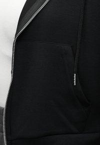 Μαύρο φούτερ με φερμουάρ μπροστά και τσέπη, με ομαλή υφή, ασημένιο φερμουάρ και κορδόνια στο καπάκι.