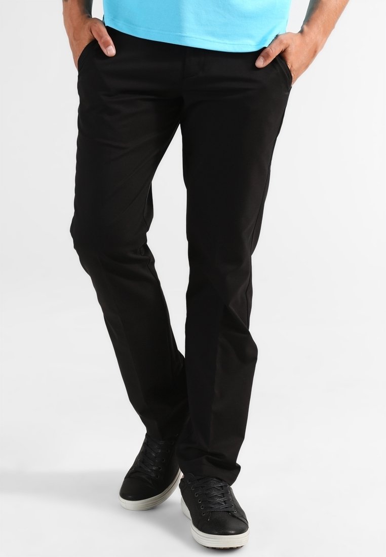 Svarta bomullschinos med en smal passform, med framfickor och en slät textur, kombinerade med svarta sneakers.