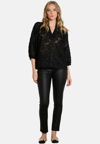 Black sheer blouse with floral texture, button front, and 3/4 sleeves, paired with black fitted pants and black flats.