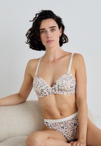 Beige en lichtbruine lingerieset met een gespikkeld patroon, beschikt over een soepele textuur, verstelbare bandjes en een contrasterende band op de slip.