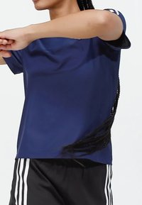 Marinblå tränings-t-shirt med korta ärmar, slät yta och rymlig passform, kombinerad med svarta shorts med vita vertikala ränder.