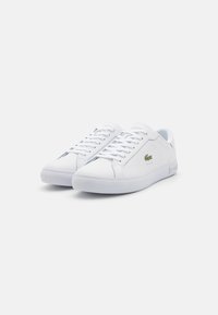 Sneakers bianchi con una superficie superiore in sintetico liscio, design con lacci, un piccolo logo verde sul lato e una spessa suola in gomma bianca.
