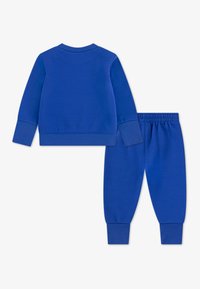 Set format dintr-un tricou și pantaloni din bumbac albastru, cu mansete și talie cu nervuri. Materialul are o textură fină și un design de culoare solidă.