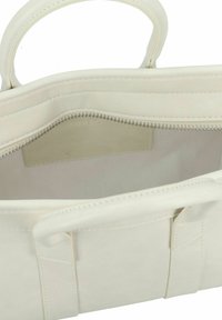 Borsa a mano bianca in pelle con dettagli cuciti, texture liscia e apertura con zip. L'interno è foderato e presenta una stampa con logo sottile.