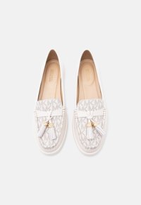 Ζευγάρι λευκά loafers Michael Kors με μπεζ μοτίβο μονόγραμμα, λεπτομέρειες με φούντες και μαλακές ταμπά εσωτερικές σόλες σε λευκό φόντο.