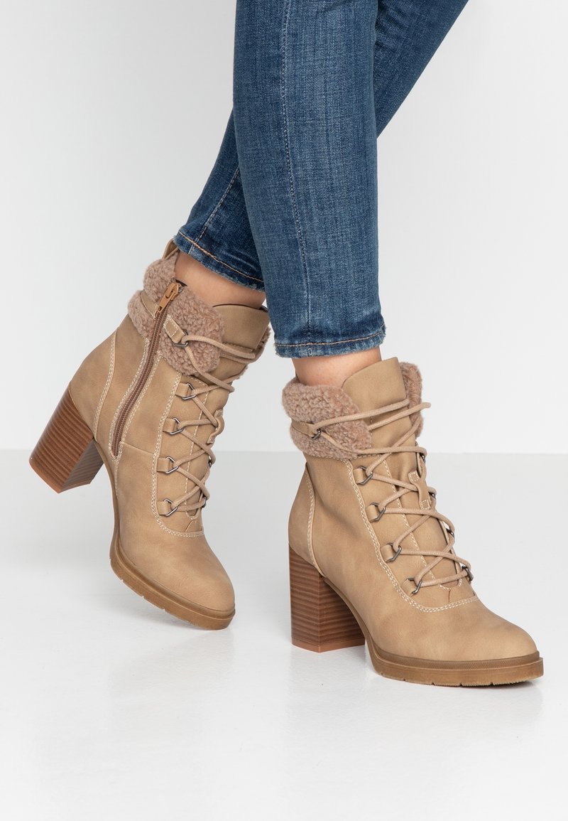 Brązowe lśniące botki za kostkę na sznurowanie z sztucznym futerkiem, brązowy drewniany blokowy obcas oraz zamek błyskawiczny po boku. Gładki skórzany materiał z teksturowanymi akcentami.