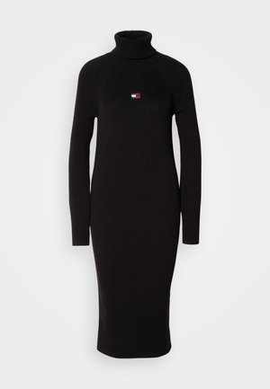 Black ribbed knit dress with a high neckline, long sleeves, and a fitted silhouette, featuring a small logo detail on the chest.