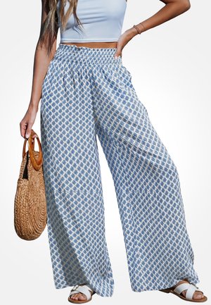 Spodnie o szerokich nogawkach wykonane z lekkiego materiału w niebiesko-biały wzór liści, z elastycznym paskiem w talii, zestawione z płaskimi sandałami.