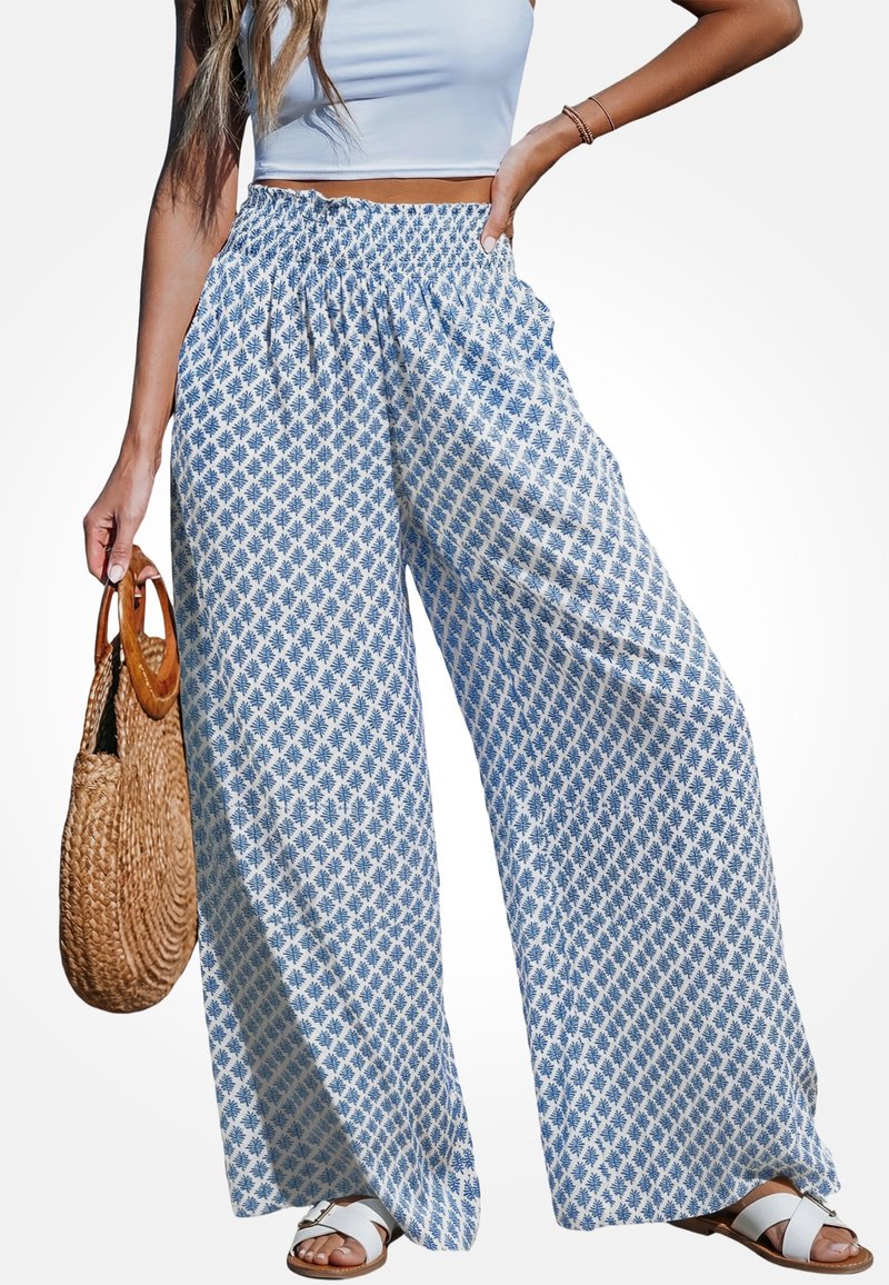 Wijde broekspijpen gemaakt van lichtgewicht stof met een blauw-wit bladpatroon, voorzien van een elastische tailleband en gecombineerd met platte sandalen.