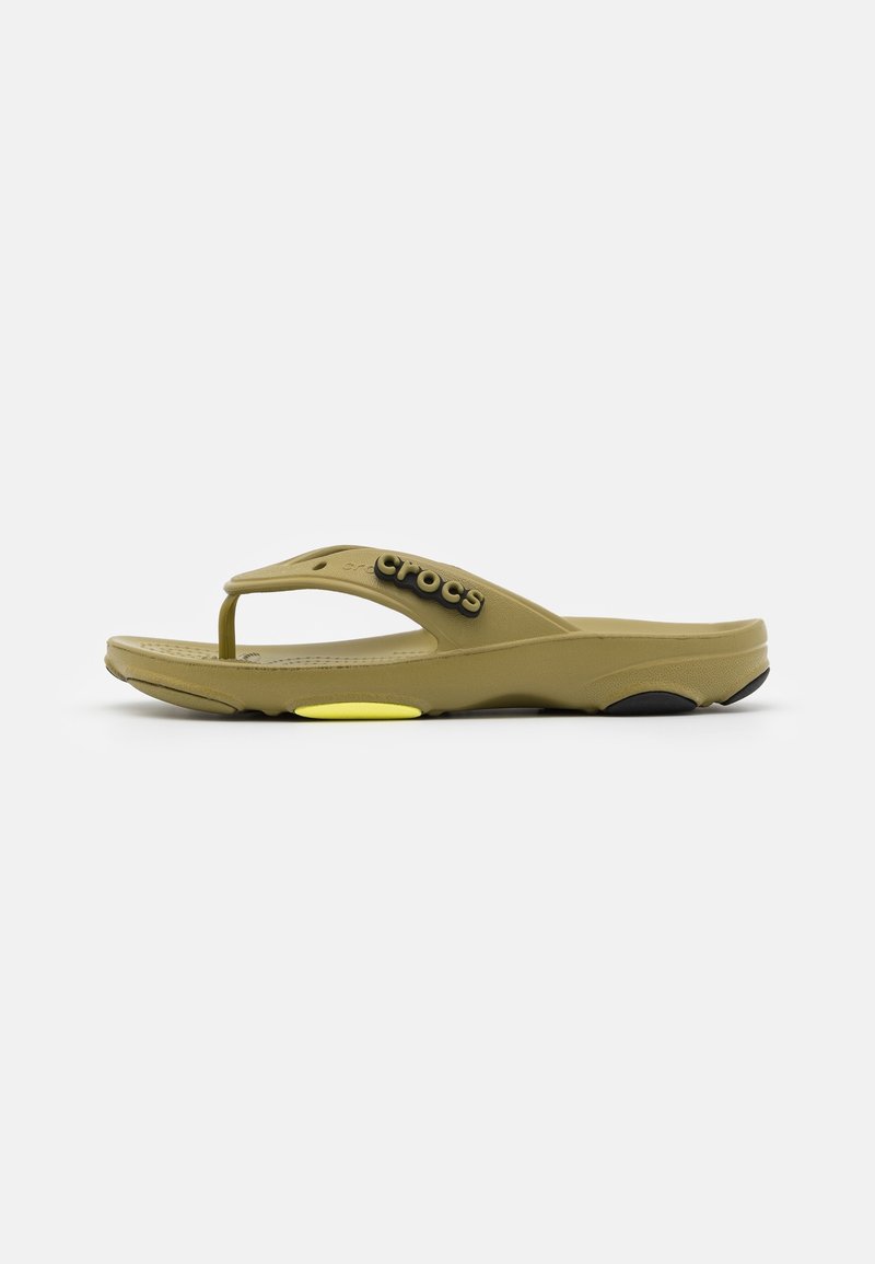 Sandale en caoutchouc de couleur vert olive avec une semelle type flip-flop. Présente un design incurvé, un logo sur la lanière et des accents contrastants en jaune et noir.