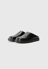 Sorte slip-on klogs med en glatt, blank overflate, avrundet tå og flat såle med horisontale spor for forbedret grep.