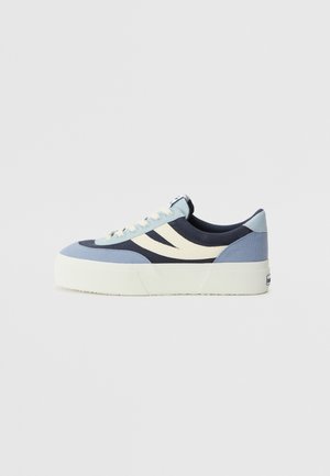 Platform sneakers in blue, navy, and cream canvas. Features two curved side stripes, laces, and textured outsole for grip.