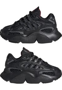 Black athletic shoes featuring a mesh upper with synthetic overlays, chunky rubber sole, and three-stripe detailing across the sides.