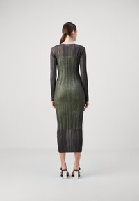 Abito in maglia con maniche lunghe, caratterizzato da un motivo a strisce verticali verdi e nere, forma aderente e lunghezza a metà polpaccio. Dettaglio con scollatura quadrata.
