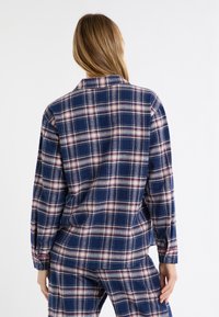 Granatowa flanelowa koszula w białą i czerwoną kratę, z długimi rękawami i mankietami na guziki, z klasycznym kołnierzem i luźnym krojem.