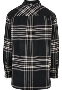 Chemise à manches longues à carreaux noir et blanc, vue de dos.