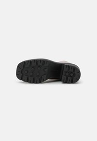 Black rubber shoe sole with a patterned tread featuring circular and rectangular details, designed for traction and durability.