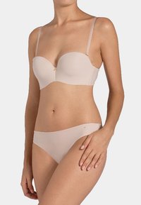 Beige trägerloser BH mit glatten Cups, verstellbaren Trägern und einem dezenten goldenen Akzent. Passende Bikiniunterteile mit glatter Textur.