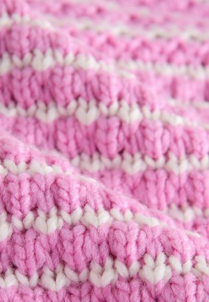 Közelkép puha kötött anyagról, rózsaszín és fehér fonalakból kialakított vízszintes csíkokkal és texturált mintával.