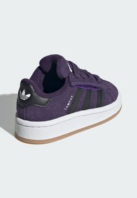 Ljubičaste suede tenisice s crnim kožnim naglascima, tri crne pruge, bijela srednja podloga i gumeni potplat; zaobljeni dizajn prstiju.