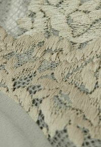 Kantstof in beige en lichtgrijs, met een bloemmotief, een gestructureerd oppervlak en fijne details met een zachte, doorschijnende uitstraling.