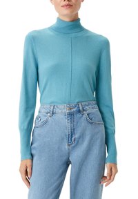 Maglione a dolce vita turchese realizzato in morbido tessuto a maglia, con maniche lunghe e un dettaglio di cucitura sulla parte anteriore, abbinato a jeans azzurri.