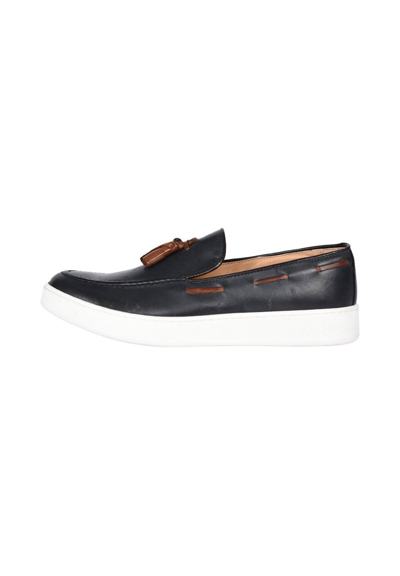 Scarpe slip-on in pelle nera con un accento in pelle marrone e suola in gomma bianca. Il design include dettagli di cucitura lungo i lati.
