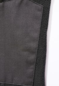 Svart tekstil med jevn overflate og rutenettmønster på den ene siden, kontrastert av en lodden tekstur på den andre. Har ren søm.