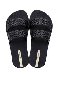Sandales noires à glissière avec deux brides texturées au motif tissé. La semelle intérieure présente un design géométrique et un accent doré sur la semelle.