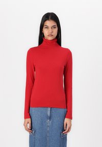 Rød langermet høyhalset topp laget av glatt stoff, tettsittende design, med høy krage og ren kant. Kombinert med et denimskjørt.