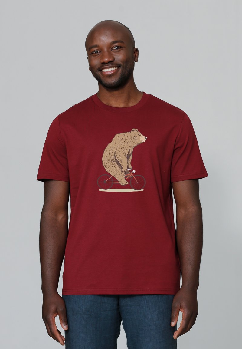 Burgunderfarbenes T-Shirt mit einer Bärenillustration, der Fahrrad fährt. Hergestellt aus Baumwolle mit kurzen Ärmeln und Rundhalsausschnitt.